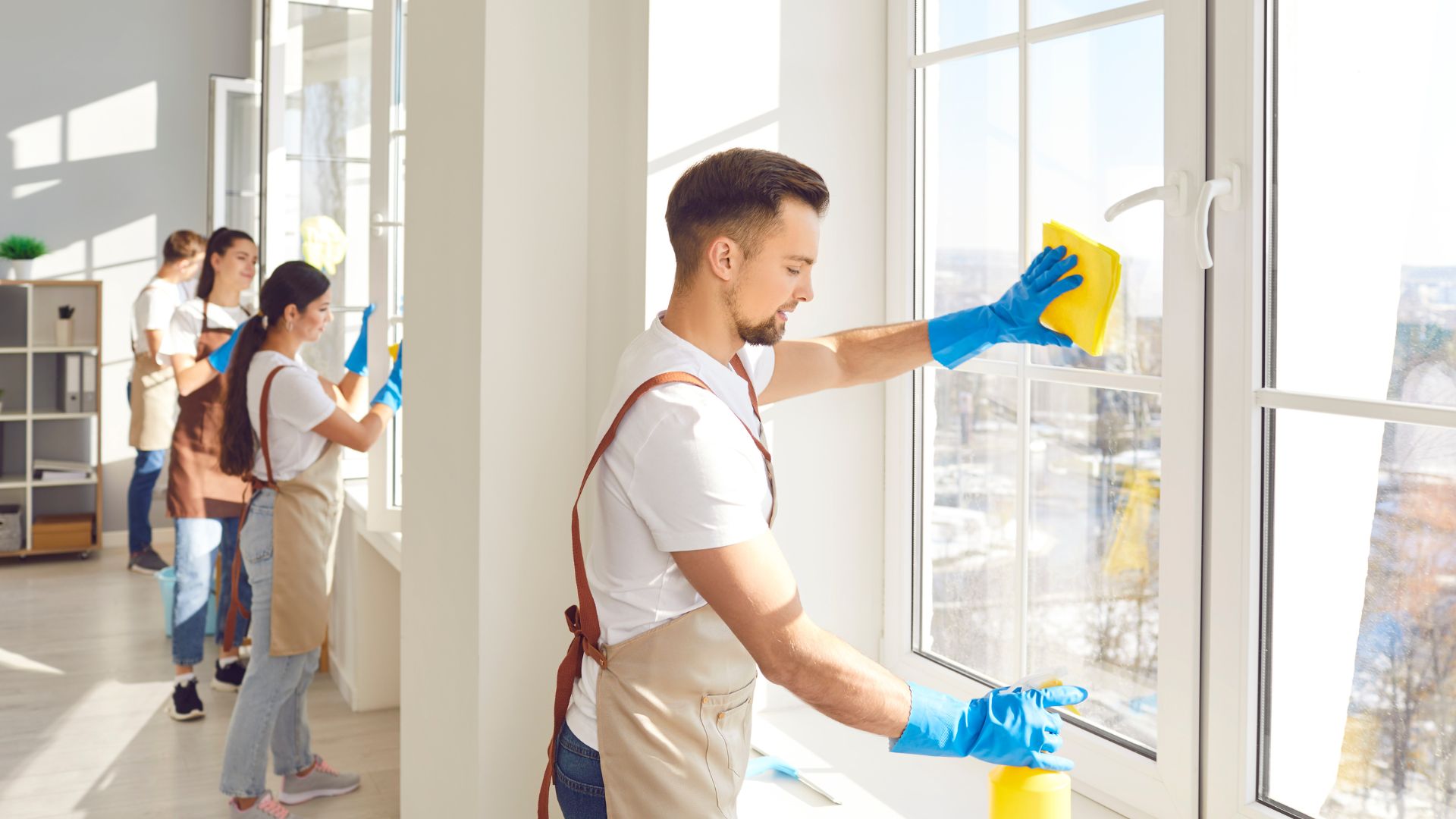 Cleaning team wiping windows in bright, modern office space